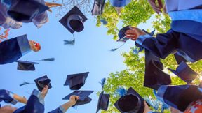 Los estudiantes de posgrado lanzan al aire sus sombreros de doctorado.